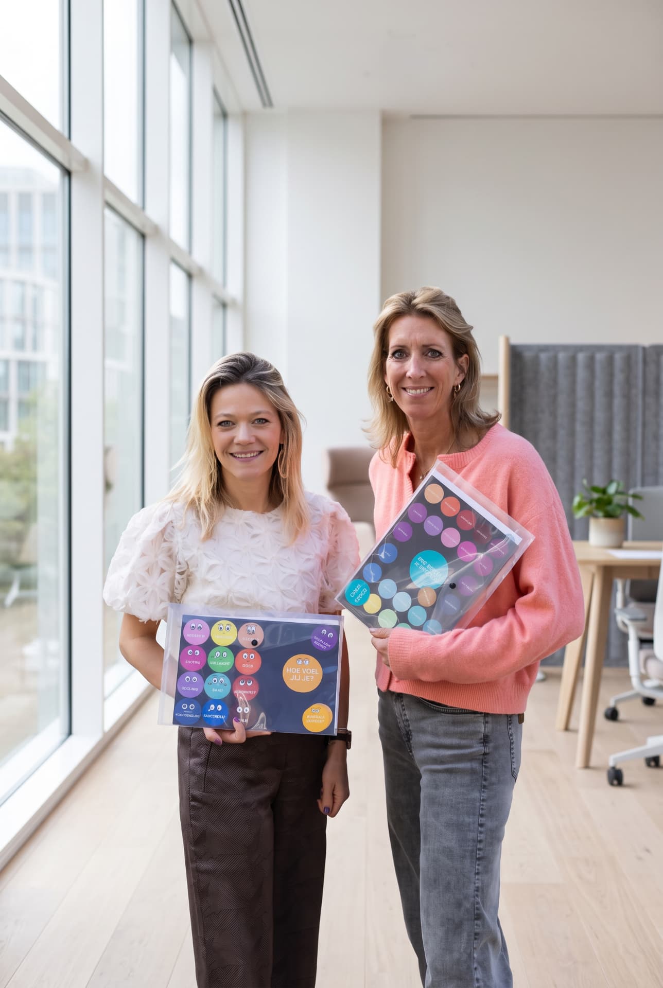 Juliette en Liselot van Vital Workplace met de Mood Wall mappen in hun handen op kantoor